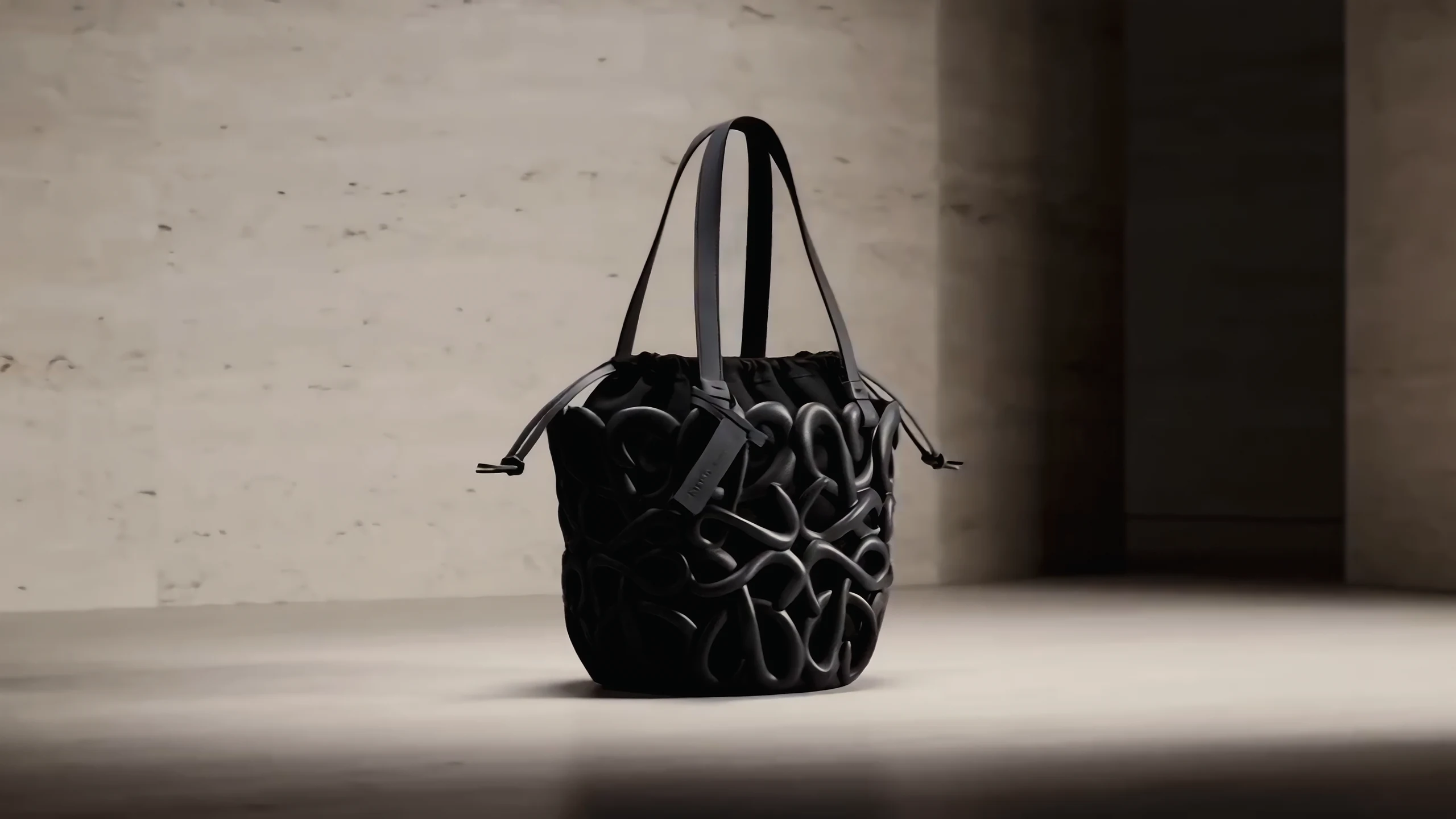 The bag on a travertine plinth beside a shadowed doorway.